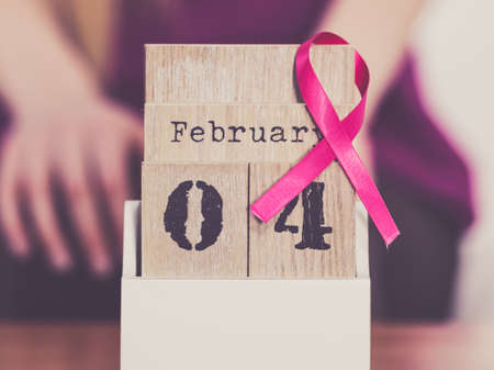 Woman and calendar, it is 4 february world breast cancer day, date with pink awareness ribbon. Healthcare and medicine concept.の写真素材
