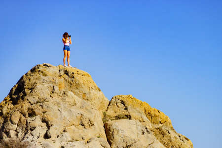 Tourist woman on rock viewpoint with camera taking travel photo.の写真素材