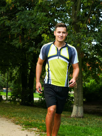 Young handsome guy in sportswear suit running outdoors in parkの写真素材