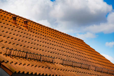 Red tiles roof with snow guards, safety barrier. House detailの写真素材