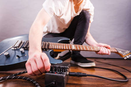 Man with musical instrument setting up guitar audio stomp box effects and cables in music studioの写真素材