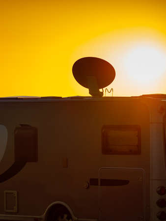 Travel holidays in motorhome. Satellite dish on roof of camper car. TV connection. Sun rising.の写真素材