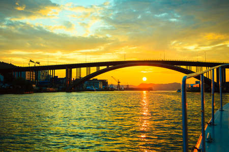 BERGEN, NORWAY - JULY 25, 2014: Evening sky above surface of the sea fjord and bridge in Bergen, Norway. View from boatの写真素材