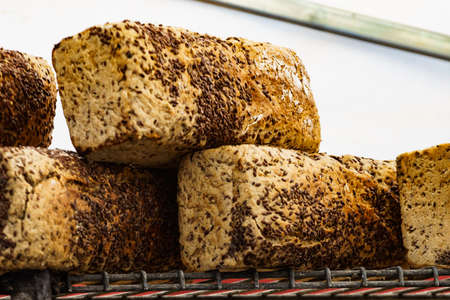 Many rustic baked traditional bread loaves on market stall outdoor.