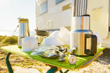 Many clean dishes outdoor on dish drying mat against camper vehicle. Washing up on fresh air....
