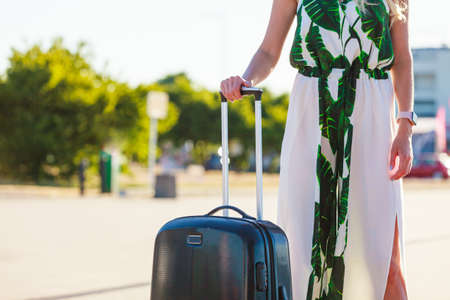 Fashionable woman arriving to new city pulling her suitcase on wheels admiring town after arrival.の写真素材