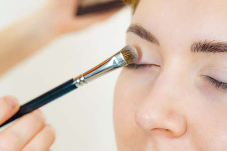 Face painting. Makeup artist applying shadows to model eye. Cosmetic beauty procedures, make up stage.の写真素材