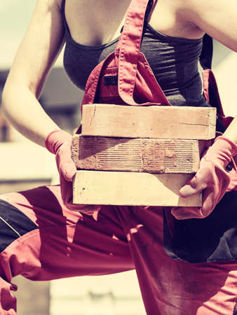 Unrecognizable woman working on construction site, building house, installing bricks. Industrial...