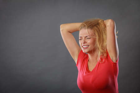 Negative human emotions, headache, face expressions, mental disorders concept. Stressed, frustrated, depressed young woman in pain holding her head and hairの写真素材