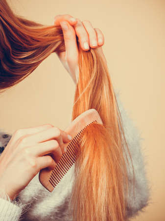 Haircare, choosing best conditioner for tangled hairstyle concept. Blonde woman brushing her hair with combの写真素材