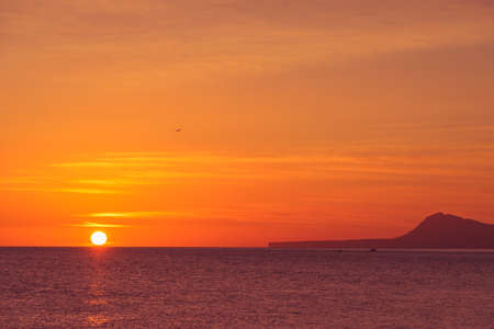 Sunrise over the sea. View from Gandia beach, Valencia Spain. Montgo mountain massif silhouetted on horizon.の写真素材