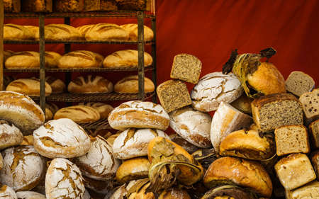 Many rustic baked traditional bread loaves on market stall outdoor.の写真素材