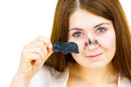 Woman removing pore cleansing textile mask, charcoal strips from nose. Girl taking care of skin complexion. Beauty treatment. Skincare.の写真素材