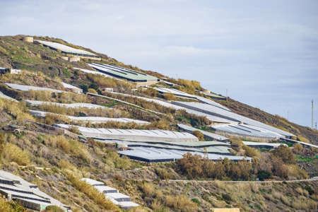 Spanish landscape and view of sea coast with many plastic greenhouses on hills. Almeria region,...