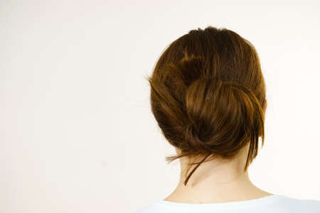 Young woman long brown hair wrapped in bun. Back view