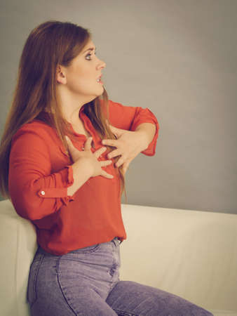 Angry, pissed off young woman. Attractive female with long brown hair sitting on sofa being mad and...
