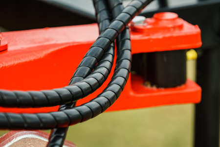 Hydraulic connections hoses in black spiral guard wraps. Machinery industrial detail