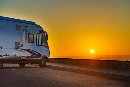 Caravan recreational vehicle at sunrise on mediterranean coast in Spain. Camping on nature. Vacation and traveling in motor home.の写真素材
