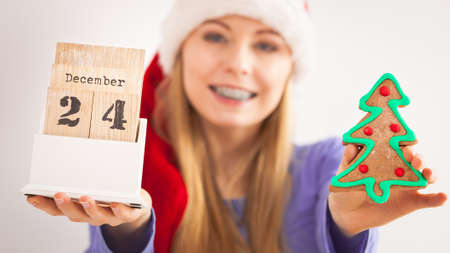 Teenage woman wearing Santa Claus christmas hat holding calendar with 24 december date and christmas...