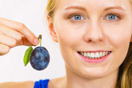 Girl holding single blue plum. Healthy seasonal fruits. Raw food diet.の写真素材