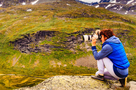 Tourist woman enjoy mountains landscape, taking travel photo with camera. National tourist scenic route 55 Sognefjellet, Norwayの写真素材