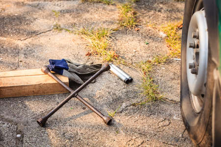 Manual socket wheel wrench and jack lying on ground. Tire car repair objects concept.の写真素材