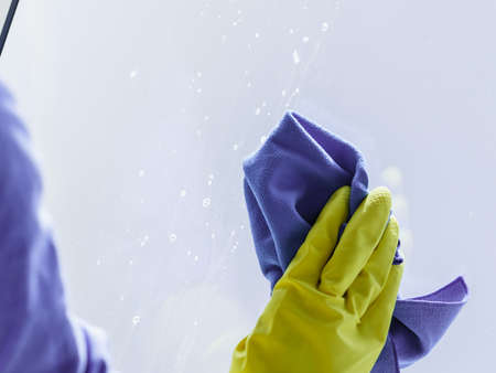Person using cloth cleaning detergent to clean window glass. House clean products, household care equipment.の写真素材