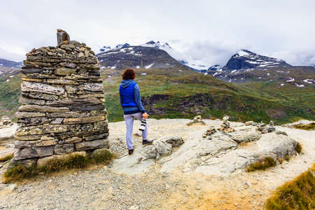 Tourist woman enjoy mountains landscape, taking travel photo with camera. National tourist scenic route 55 Sognefjellet, Norwayの写真素材