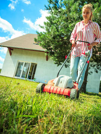 Gardening, taking care of house backyard, agricultural concept. Female person mowing green lawn with...