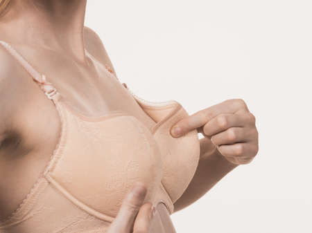 Slim young woman small boobs wearing too big bra cup. Female breast wrong size lingerie. Bosom and brafitting concept.の写真素材