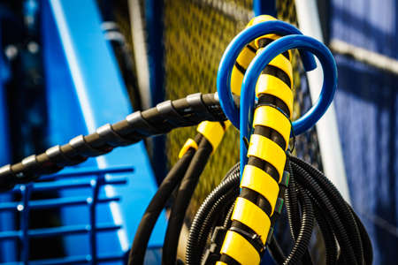 Hydraulic connections hoses in black and yellow spiral guard wraps. Machinery industrial detail
