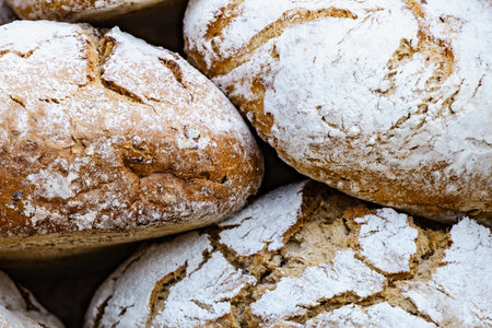 Many rustic baked traditional bread loaves on market stall outdoor.の写真素材