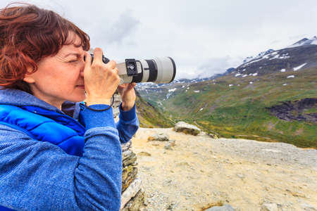 Tourist woman enjoy mountains landscape, taking travel photo with camera. National tourist scenic route 55 Sognefjellet, Norwayの写真素材