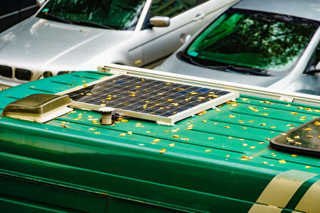 Camper van with solar panel on roof, autumn season