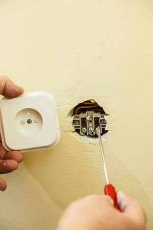 Person adjusting, removing electric power socket plug. Fixing, installing electricity, electrician...