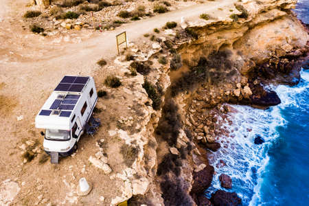 Caravan with solar panels on roof camping on cliff sea shore. Mediterranean region of Mazarron in Murcia, Spain.の写真素材