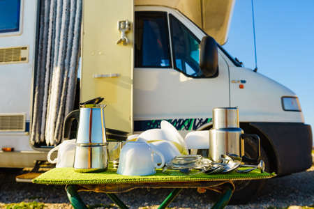 Many clean dishes outdoor on dish drying mat against camper vehicle. Washing up on fresh air....