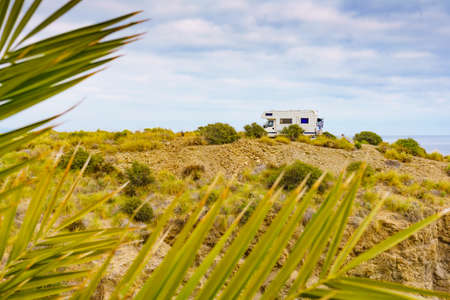 Palm tree and caravan camping on cliff above Cala Mochuela, spanish landscape along Almeria coast. Traveling in motorhome. Focus camper.の写真素材