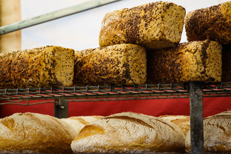 Many rustic baked traditional bread loaves on market stall outdoor.