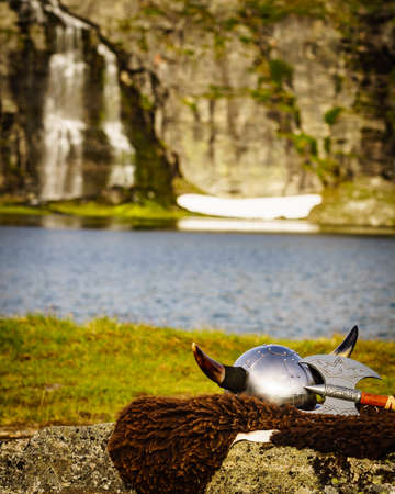 Viking helmet with axe on lake shore in Norway. Tourism and traveling concept