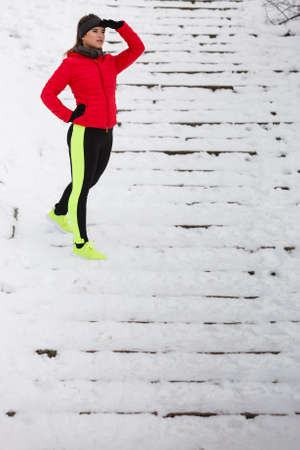 Outdoor sport exercises, sporty outfit ideas. Woman wearing warm sportswear running jogging outside during winter.の写真素材