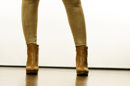 Close up of woman wearing brown suede slim fit trousers and high heels autumnal boots shoes.の写真素材