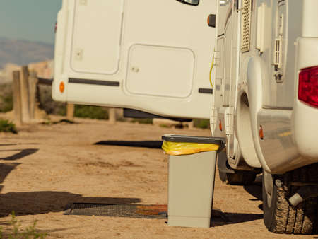 Trash can with plastic bag inside in front of caravan. Holidays and travel in motorhome.の写真素材