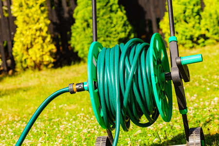 Green gardening hose for watering flowers and grass outsideの写真素材