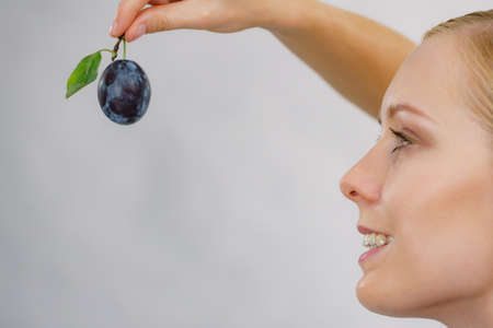 Girl holding single blue plum. Healthy seasonal fruit, organic nutrition.の写真素材
