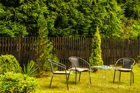 Table and chairs for rest in garden on green lawn.