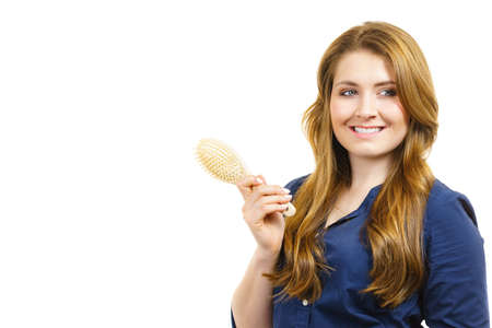 Young woman combing long healthy brown hair, using brush. Haircareの写真素材