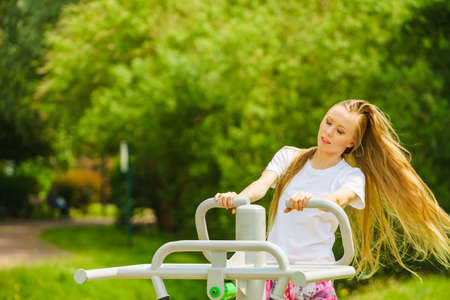 Young woman working out outside. Girl making exercises and training on public equipment in outdoor gym at park. Healthy lifestyle.の写真素材