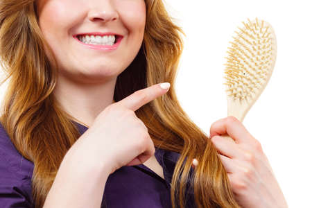 Young woman combing long healthy brown hair, using brush. Haircareの写真素材