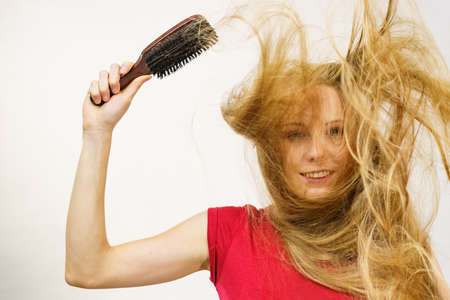 Blonde girl long blowing hair holds brush with natural bristles. Haircare, treatment concept.の写真素材